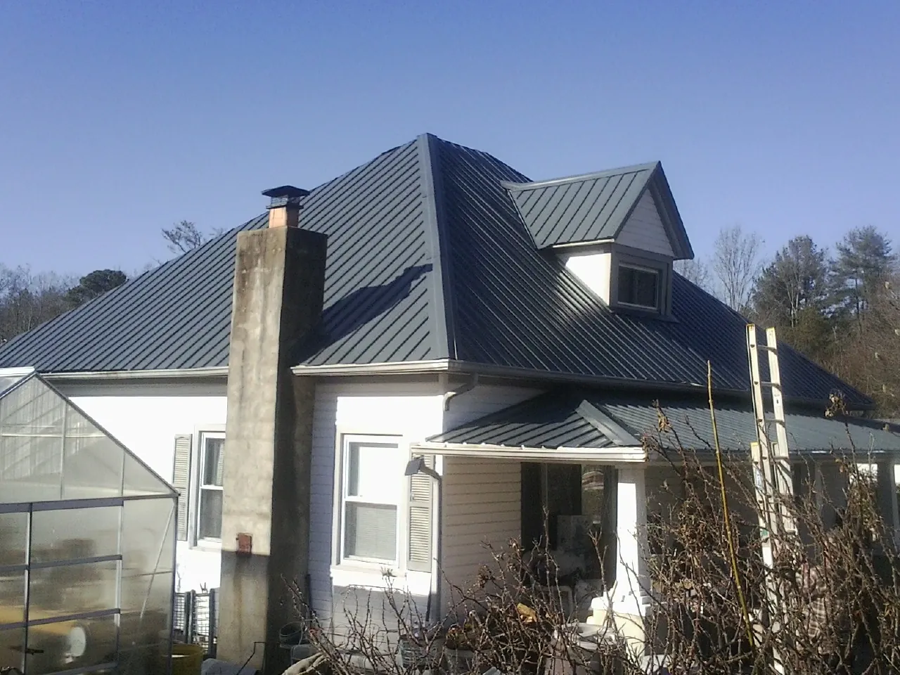 Dark blue standing seam metal roof on a white farmhouse with dormer — Slate & Tile Roof Repair by Roofing Brothers in Rancho Santa Margarita
