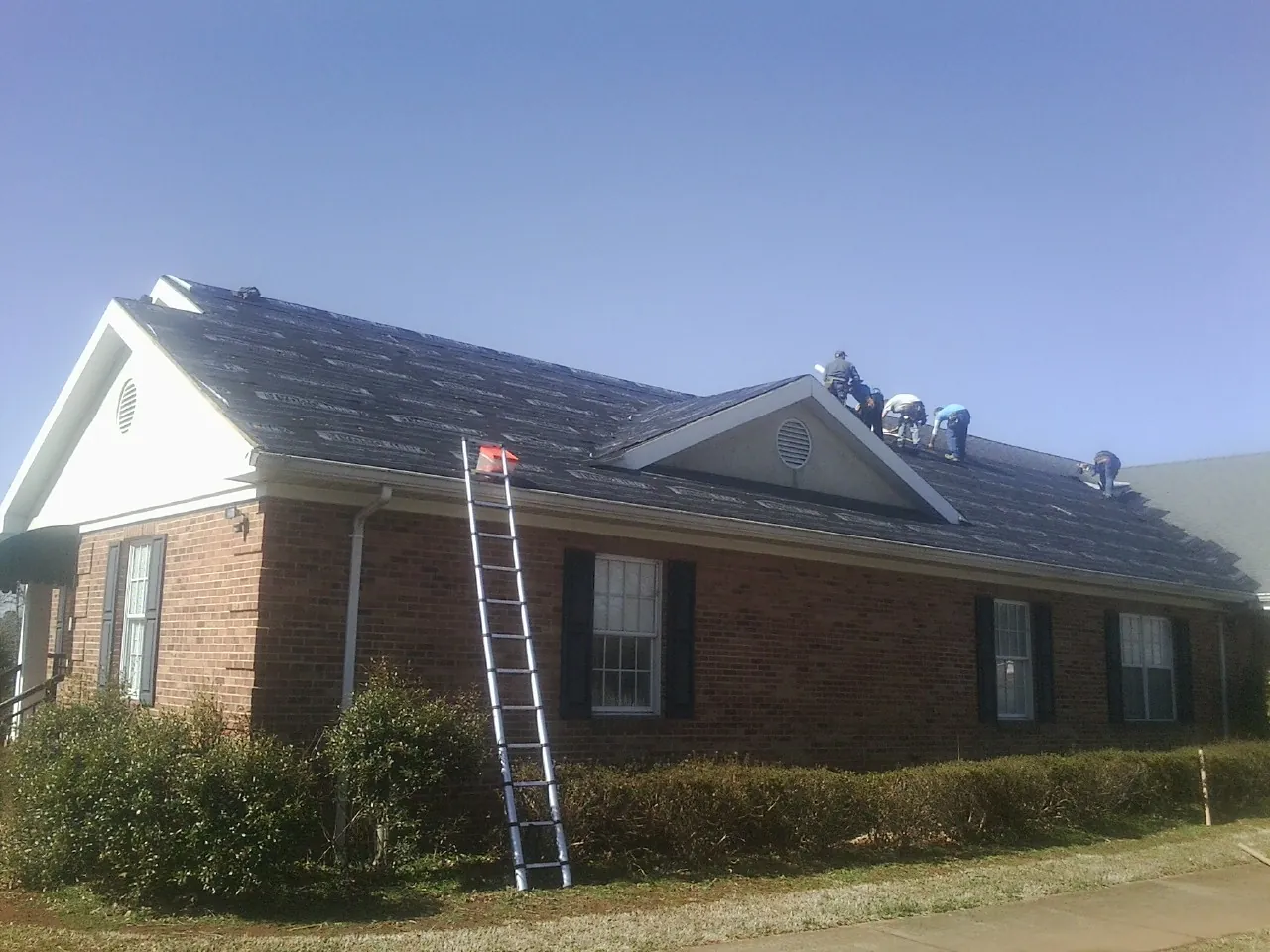 Crew tearing shingles off a brick ranch roof with a ladder set — Metal Roof Repair work by our crew in Rancho Santa Margarita