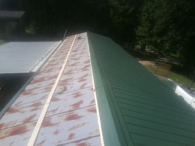 Old rusted panels beside newly installed green metal roofing — Wind Damage Roof Repair by Roofing Brothers in Rancho Santa Margarita