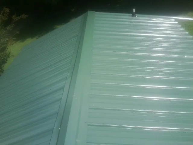 New green metal panels meeting at the ridge of a roof — Flat Roof Repair work by our crew in Rancho Santa Margarita