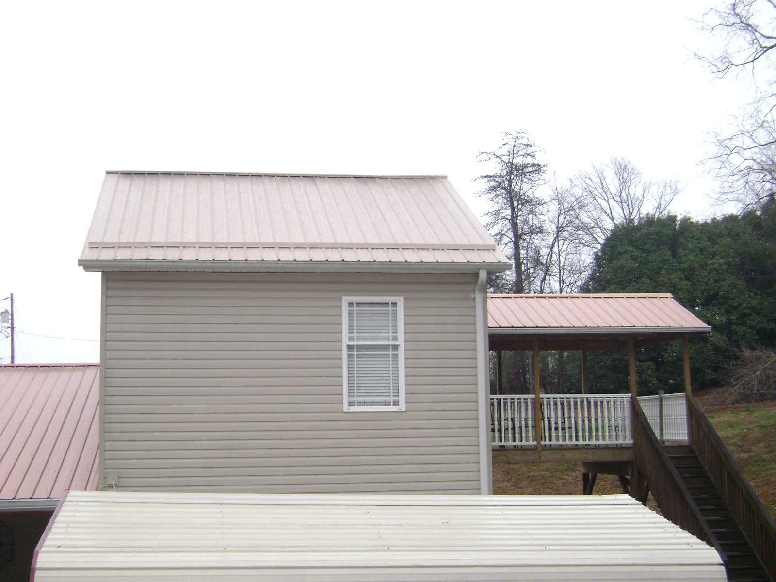 Tan metal roofs on a two story addition and attached porch, from a Roof Replacement job in Rancho Santa Margarita