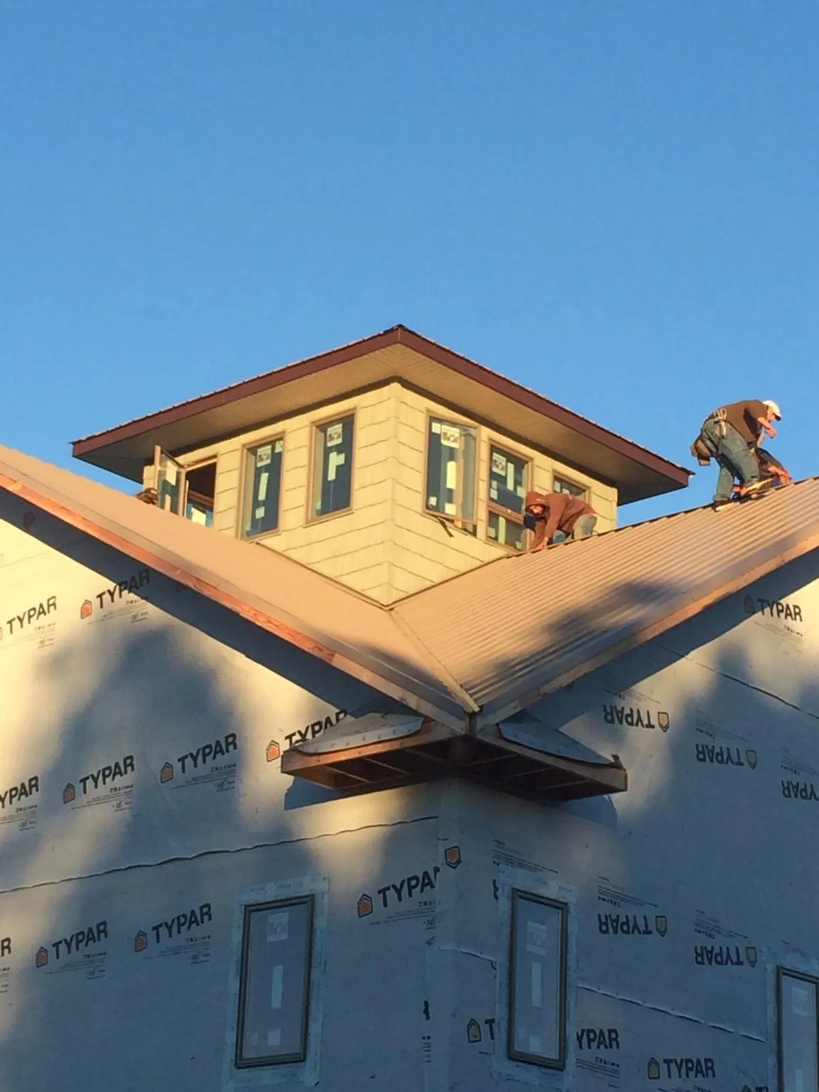 Roofers working around a rooftop cupola on a new metal roof at sunset — Roof Waterproofing in Rancho Santa Margarita by Roofing Brothers